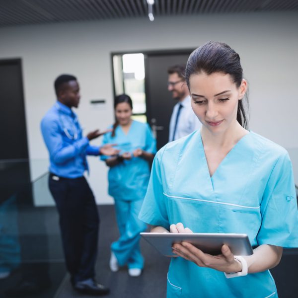 Beautiful nurse using digital tablet in hospital corridor